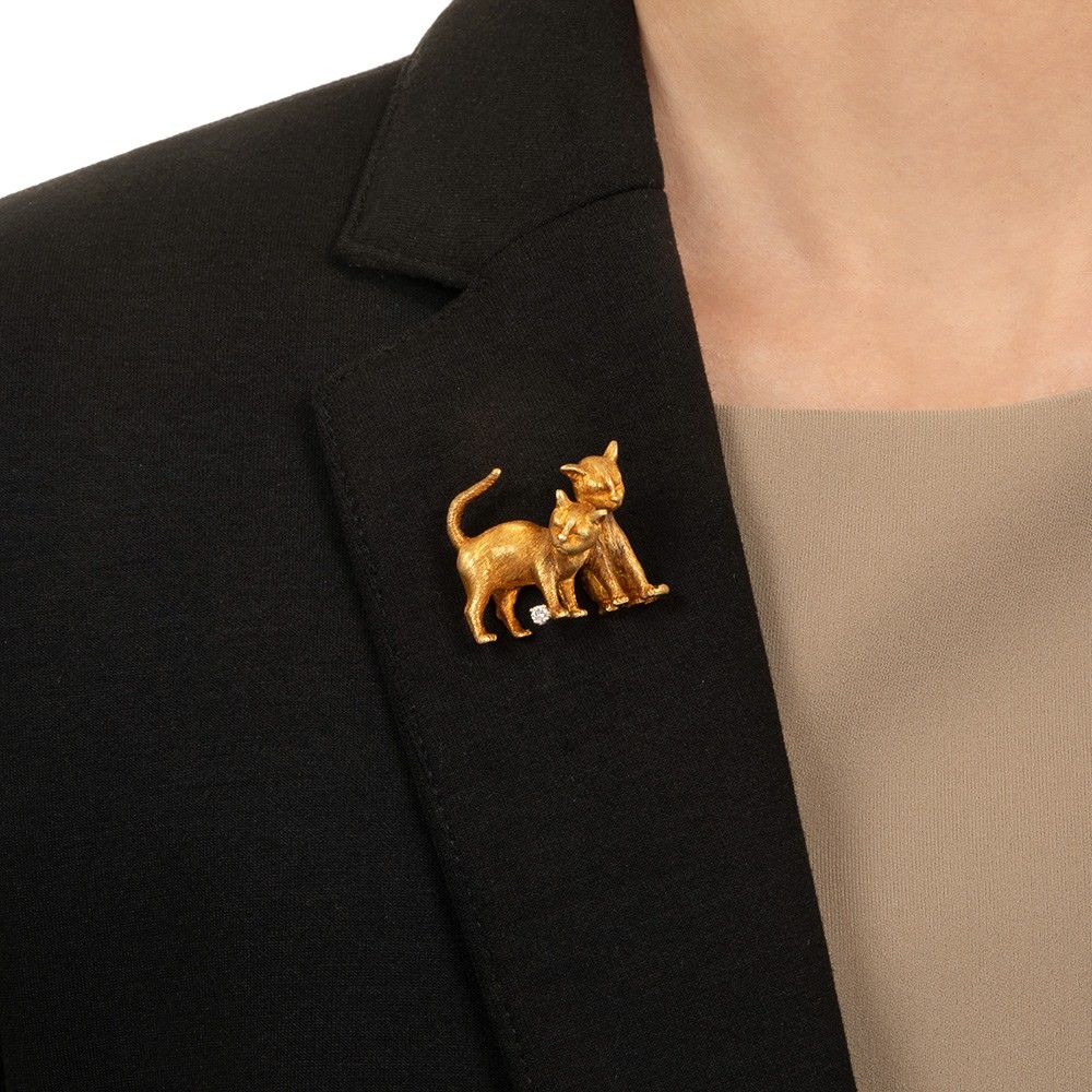 A vintage gold cat brooch pinned to a lapel, an example of the signed estate animal brooches leading six years of estate brooch demand