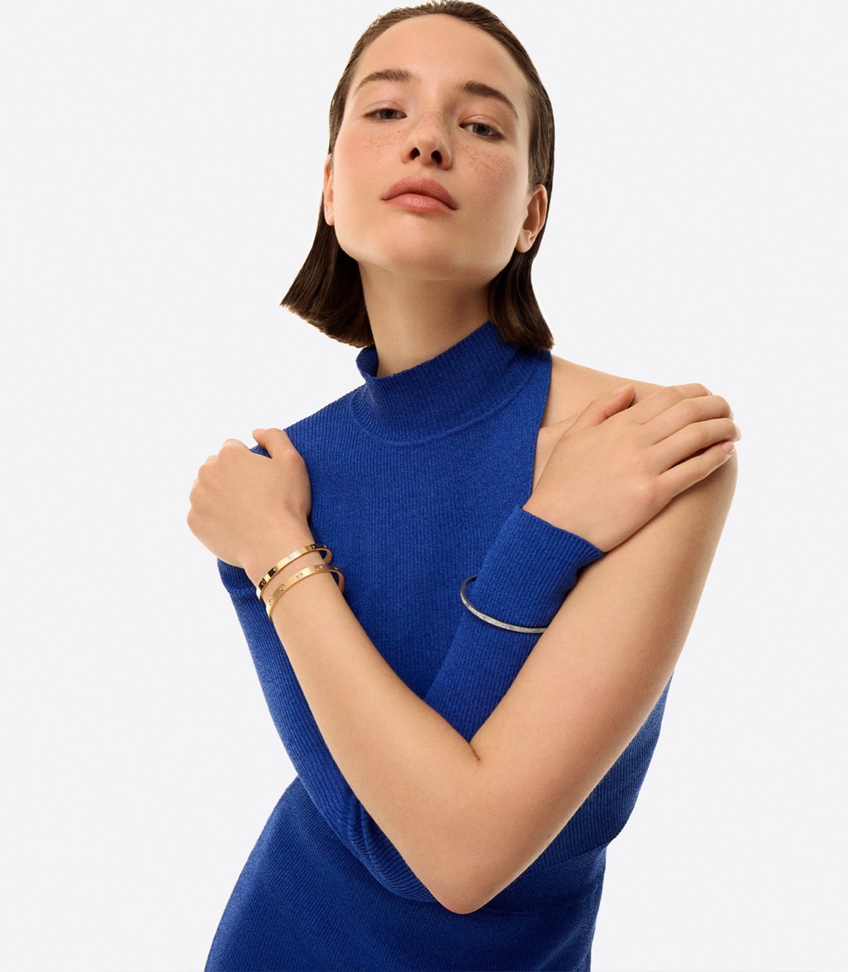 A stacked Cartier Love bracelet combination worn by a model in a cobalt turtleneck. Image courtesy of Cartier.