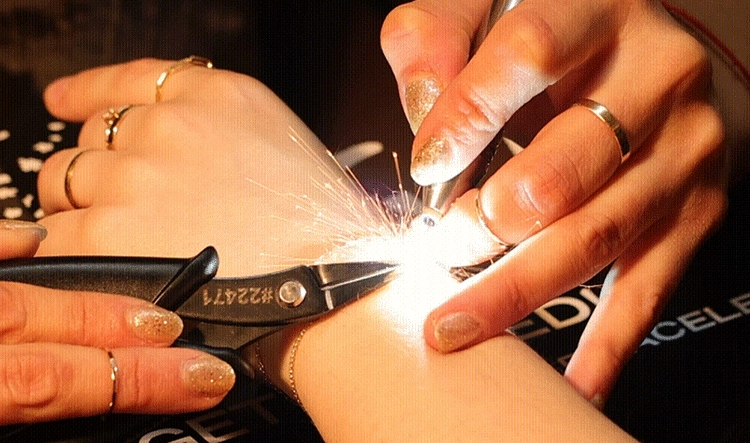 Catbird permanent jewelry welding in progress, sparks flying as a bracelet is zapped onto a wrist
