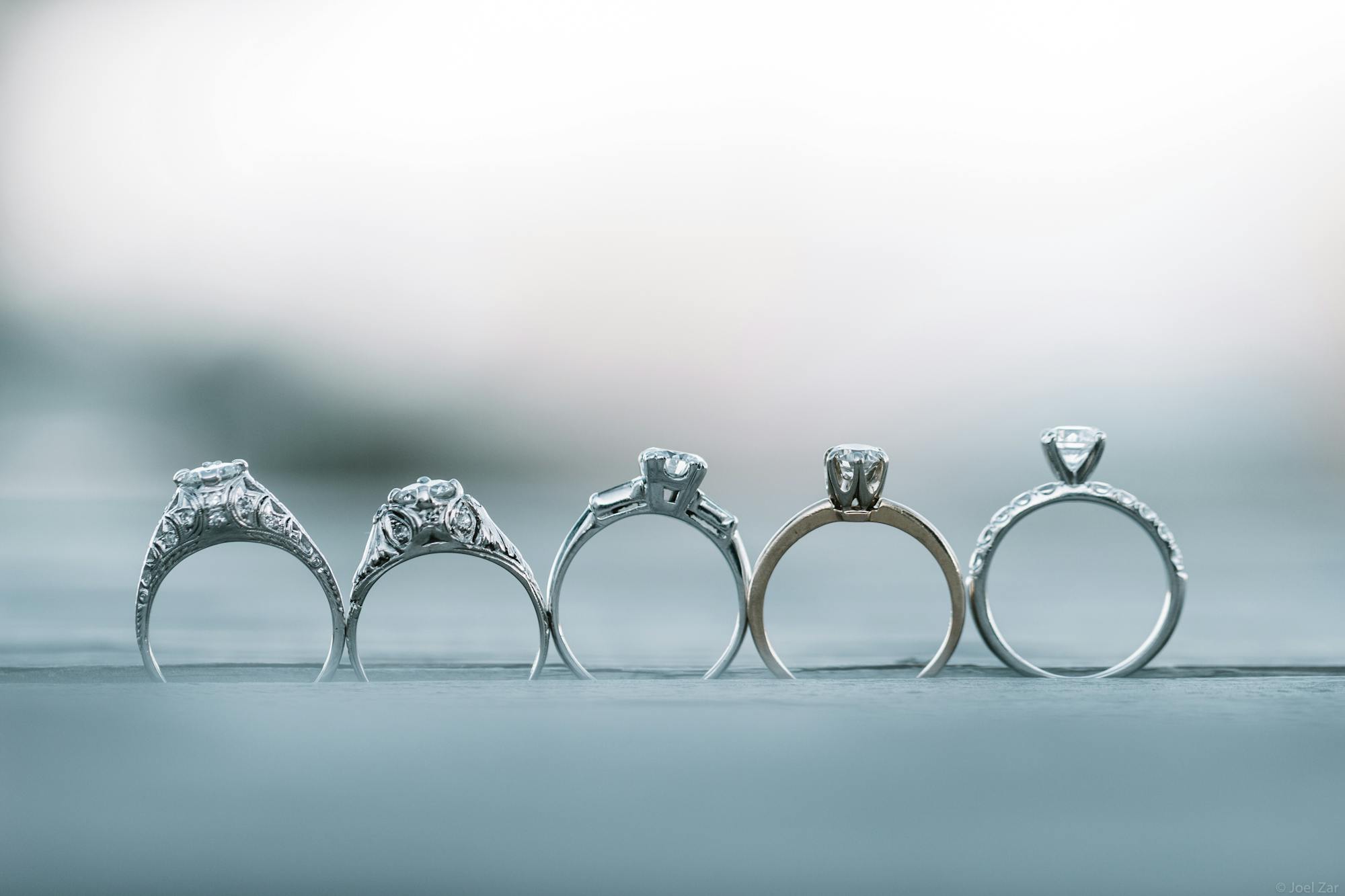 A row of five engagement rings in different settings, lined up side by side