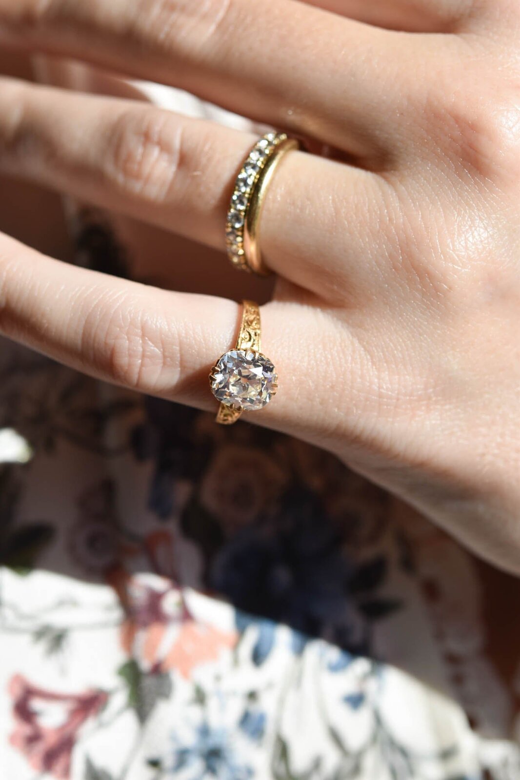 A Victorian old mine cut diamond solitaire in engraved gold worn on a hand and stacked with a band, the kind of unsigned vintage piece you can try on and wear every day, courtesy of Erstwhile Jewelry