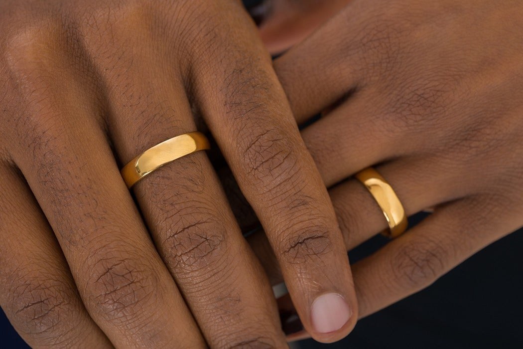 Two hands wearing plain polished gold wedding bands, one band wider than the other - the men's wedding ring was advertised into existence in the 1940s, taking double-ring ceremonies from about 15 percent of American couples to about 80 percent.