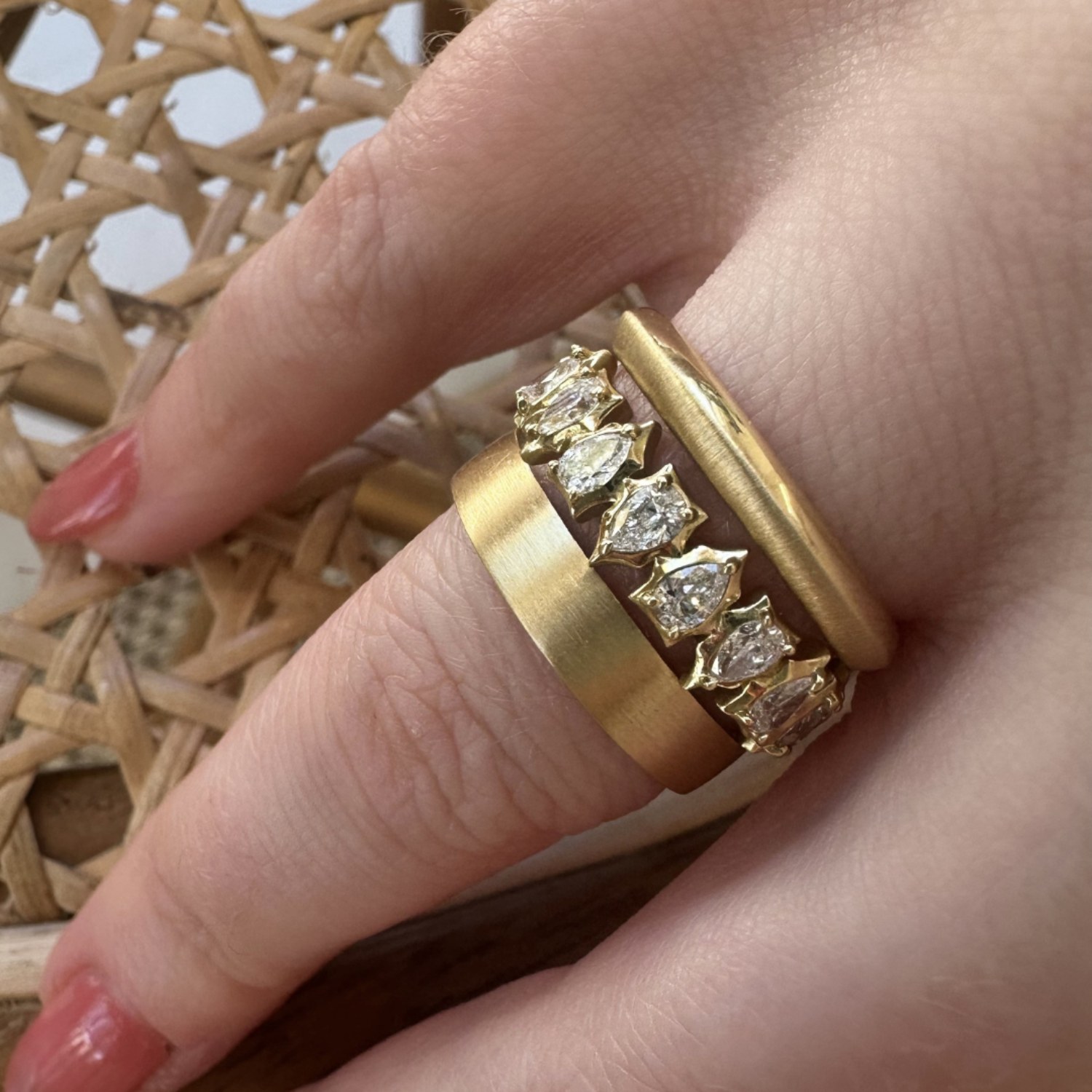 A wide brushed-gold Jade Trau Tatum flat-edge band worn beside a marquise-diamond band and a narrower rounded one - band width is a convention and the number is yours to pick, and Tatum runs the whole range under one heading, for him or her.