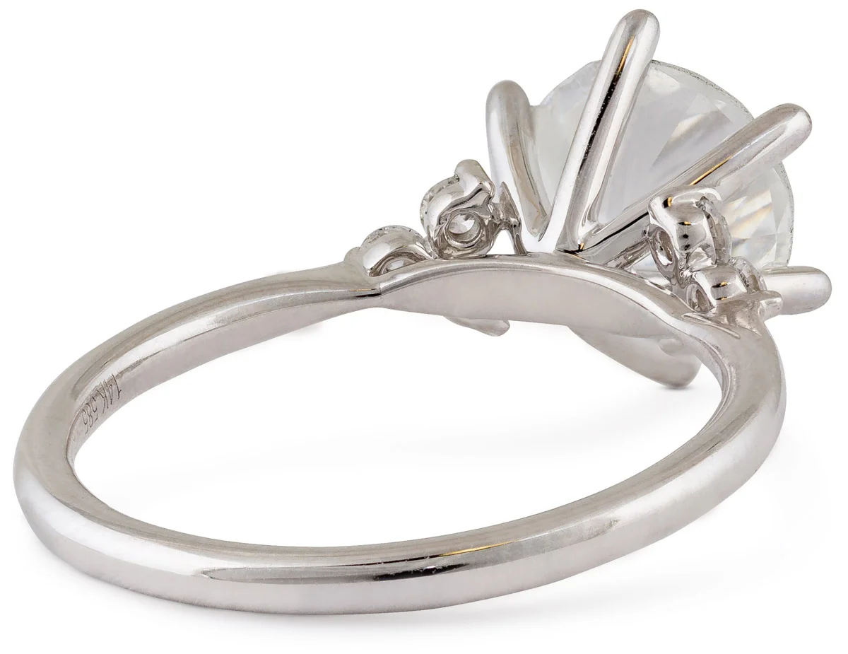 The underside of a white gold solitaire ring showing prongs, gallery, and hallmark stamp