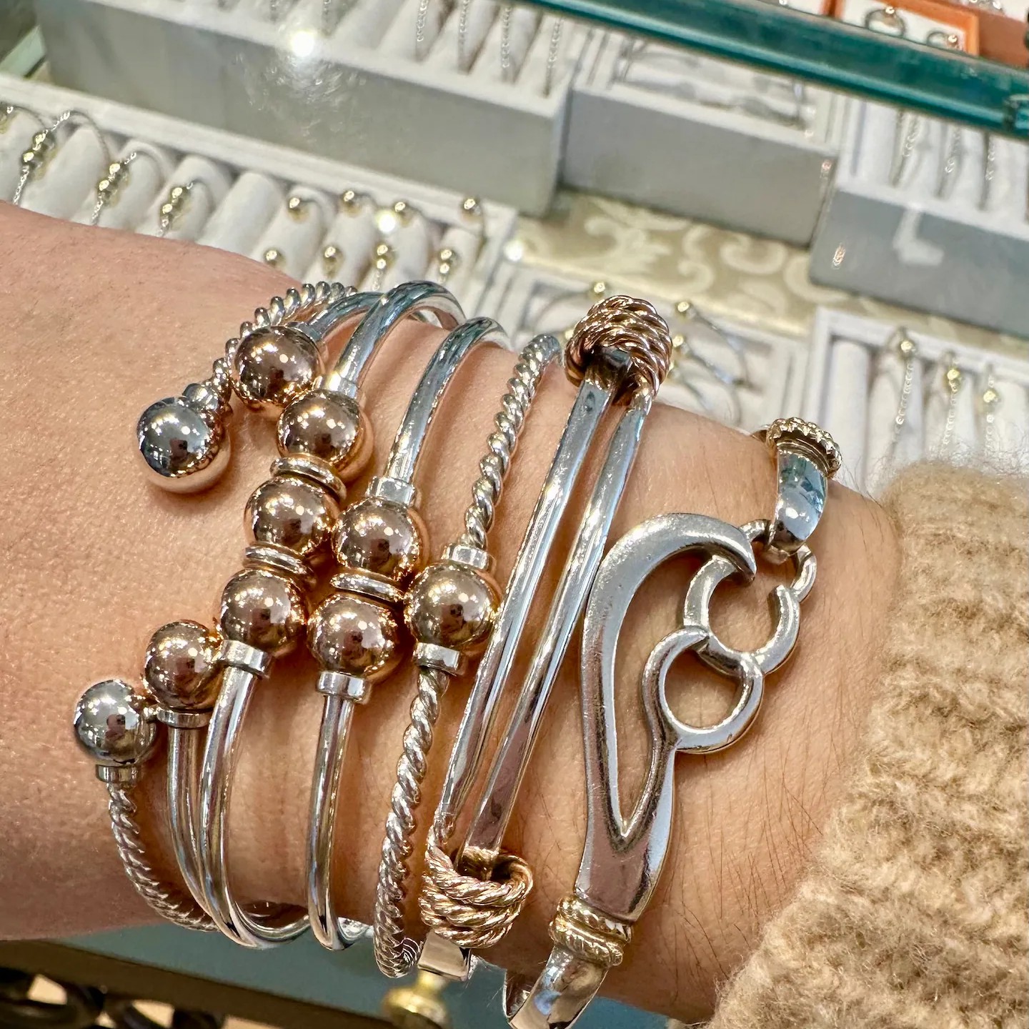 Multiple Cape Cod Screwballs stacked on a wrist, silver bangles with the characteristic gold balls and a small heart accent, the look longtime Cape buyers recognize across a room.