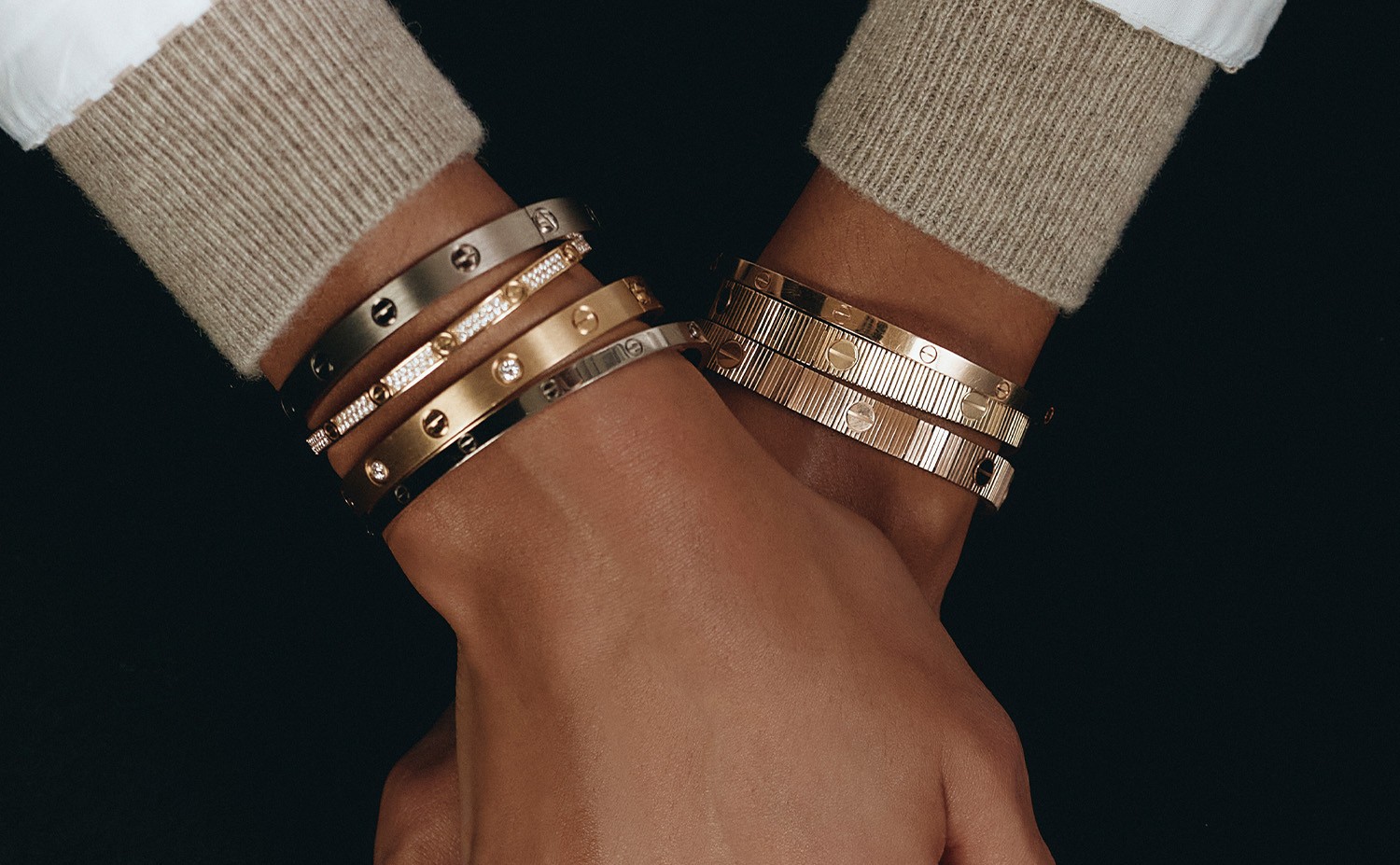 Four Cartier LOVE bangles per wrist with a row of LOVE rings. Past a point a stack stops being a sentence and just shouts one word.