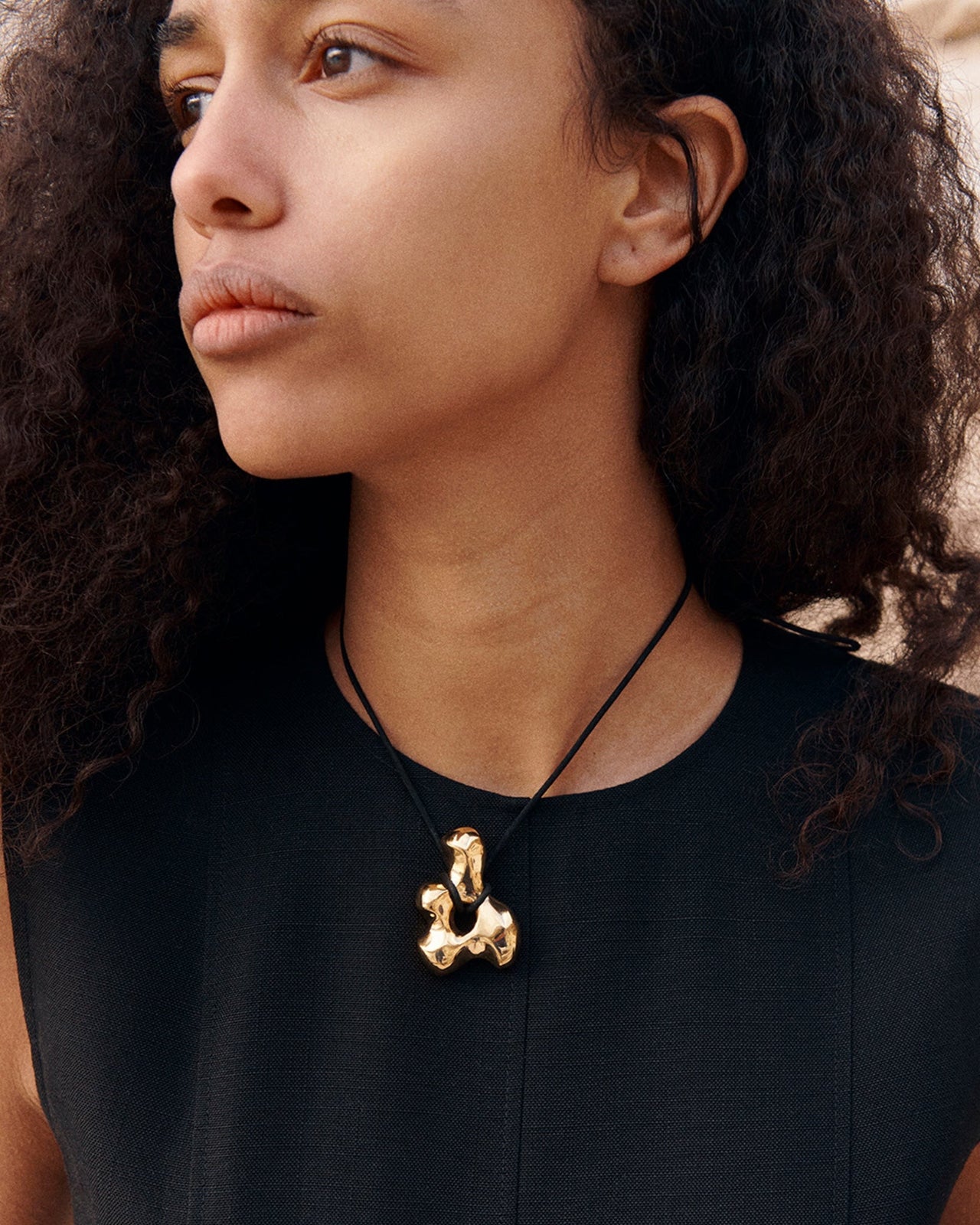 AGMES Bodmer Pendant in gold vermeil worn on the chest, a single sculptural pendant doing all the work on the neckline