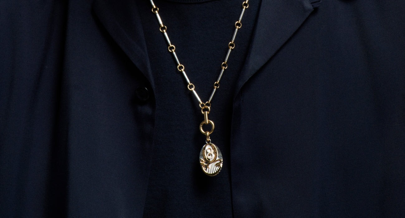 Man wearing Foundrae gold medallion on chunky chain, navy open shirt