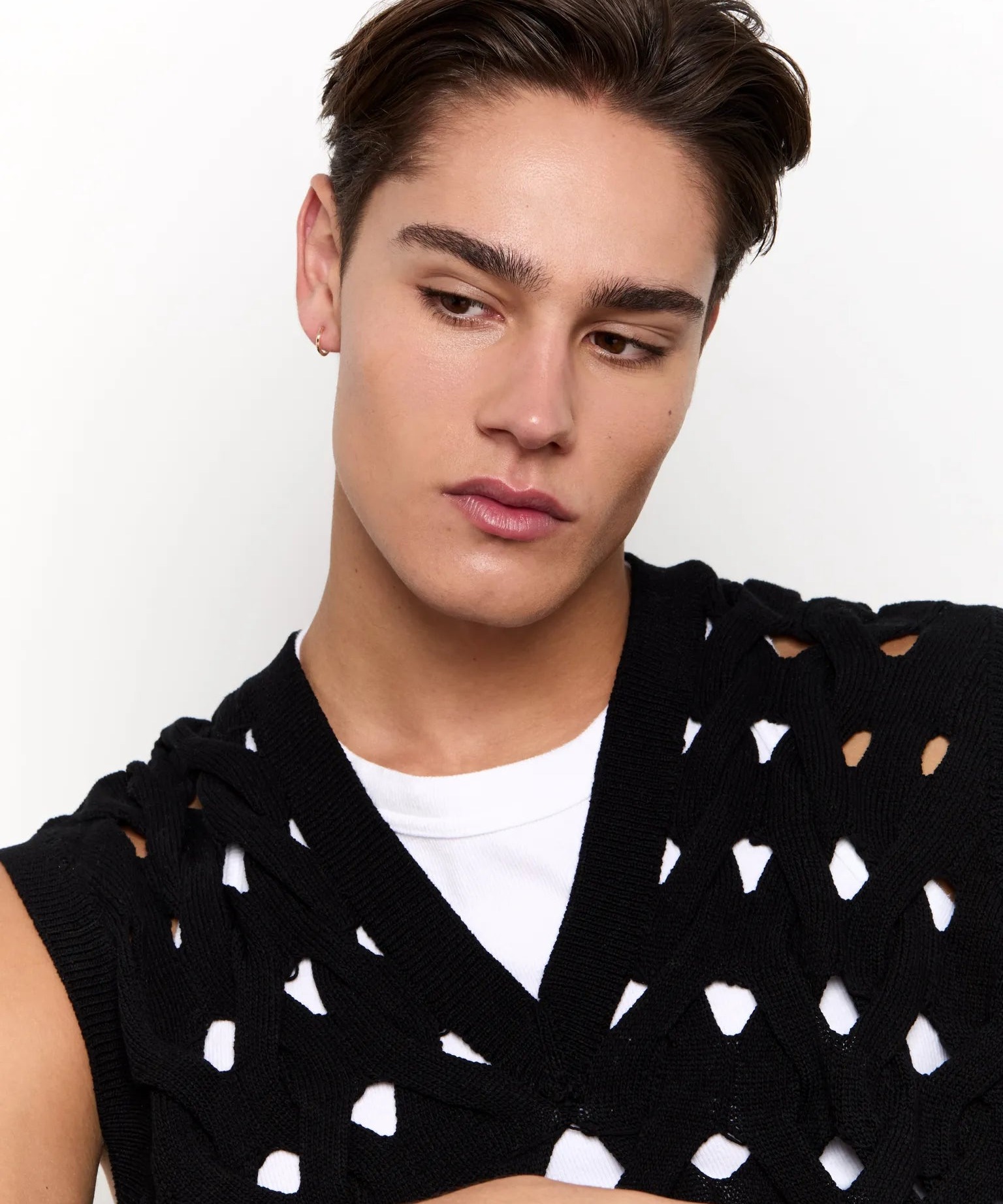 A man wears a single solid gold huggie hoop in one lobe, the single earring in solid gold that the look has normalized into rather than a stacked ear