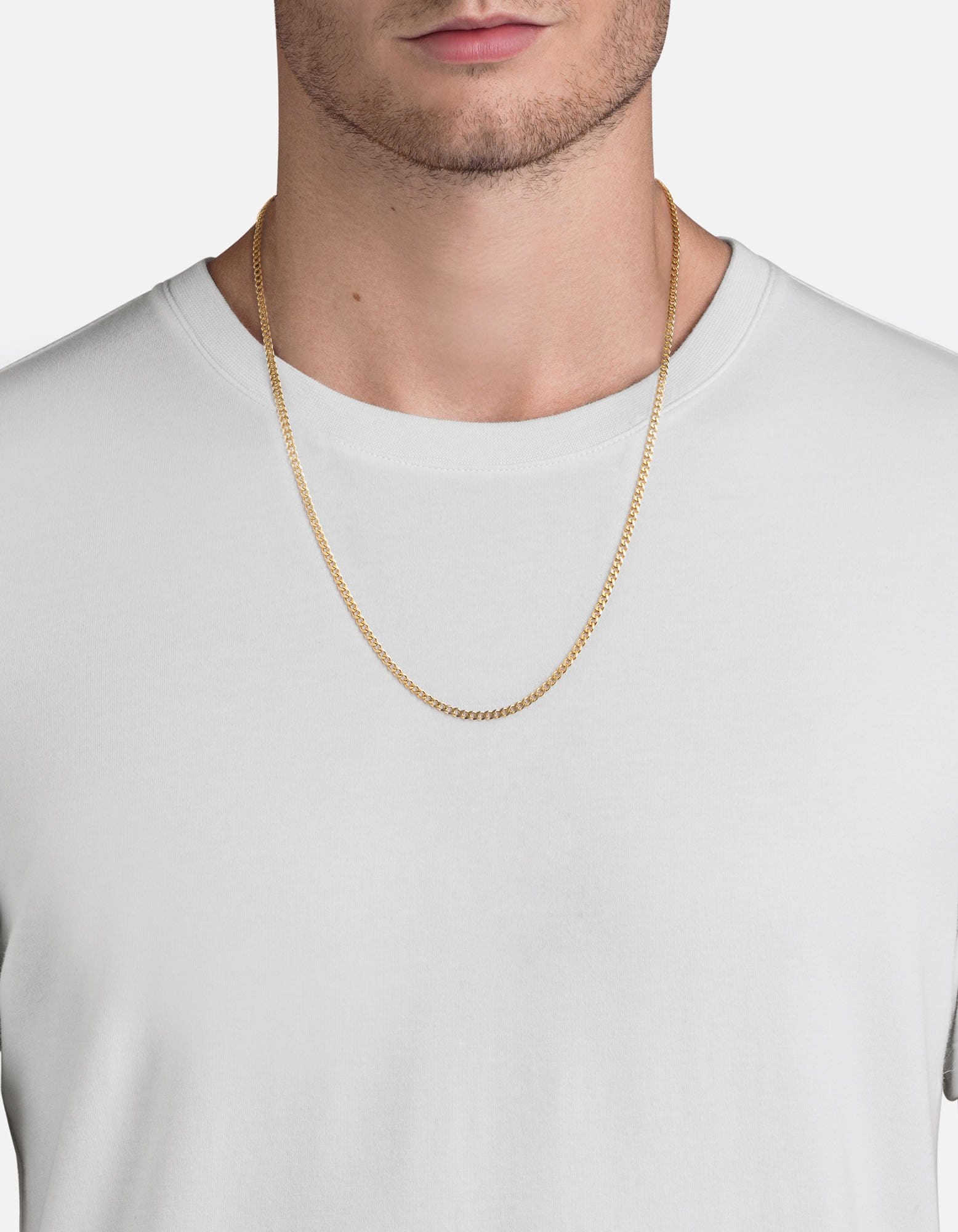A man wears a solid gold curb chain over a white tee, the ordinary day that men's fine jewelry is built for and the kind of men's gold jewelry worth buying in solid gold