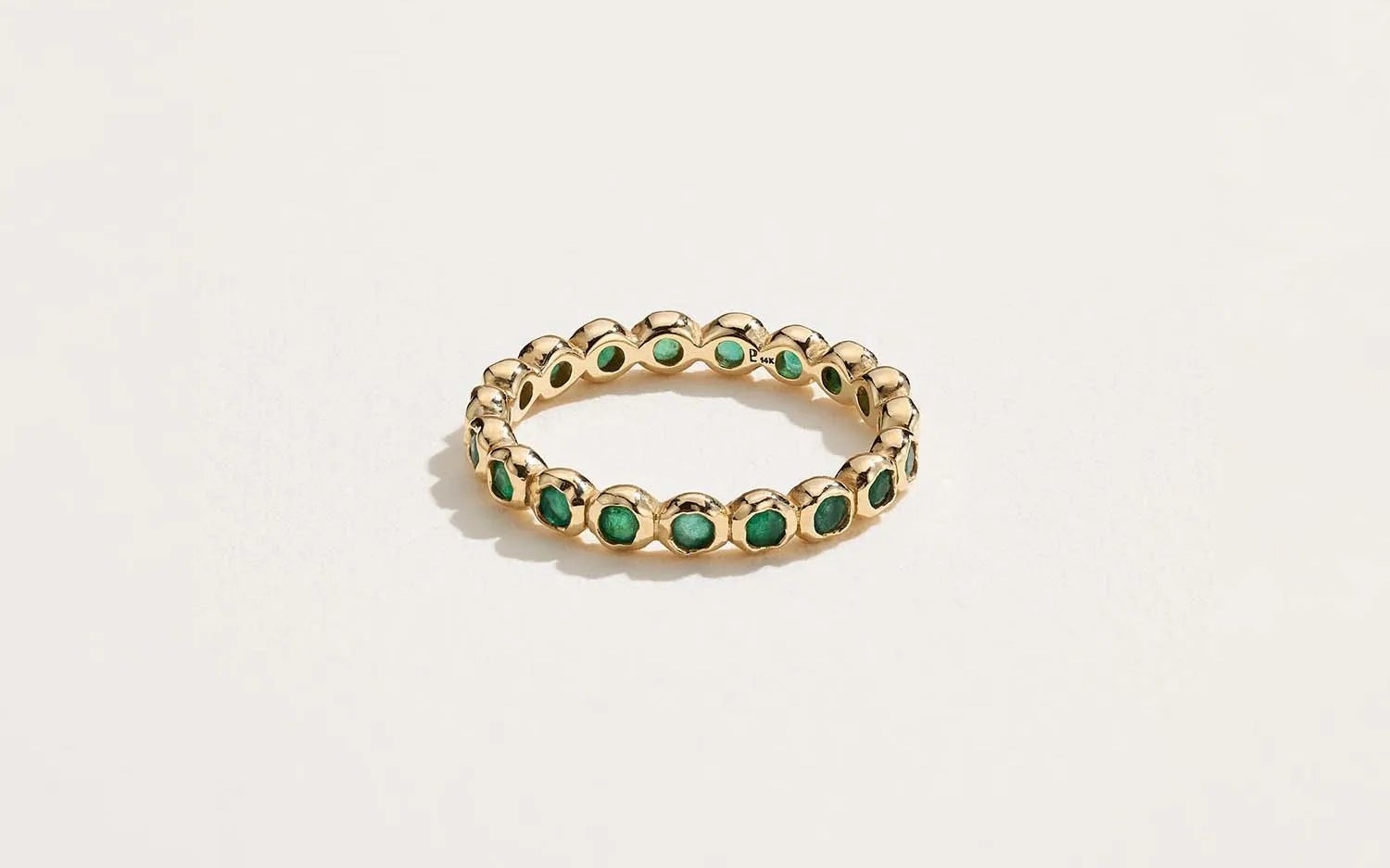 Pamela Love Molten Eternity Band in 14k yellow gold with green emerald, a sculptural gold ring with fluid texture
