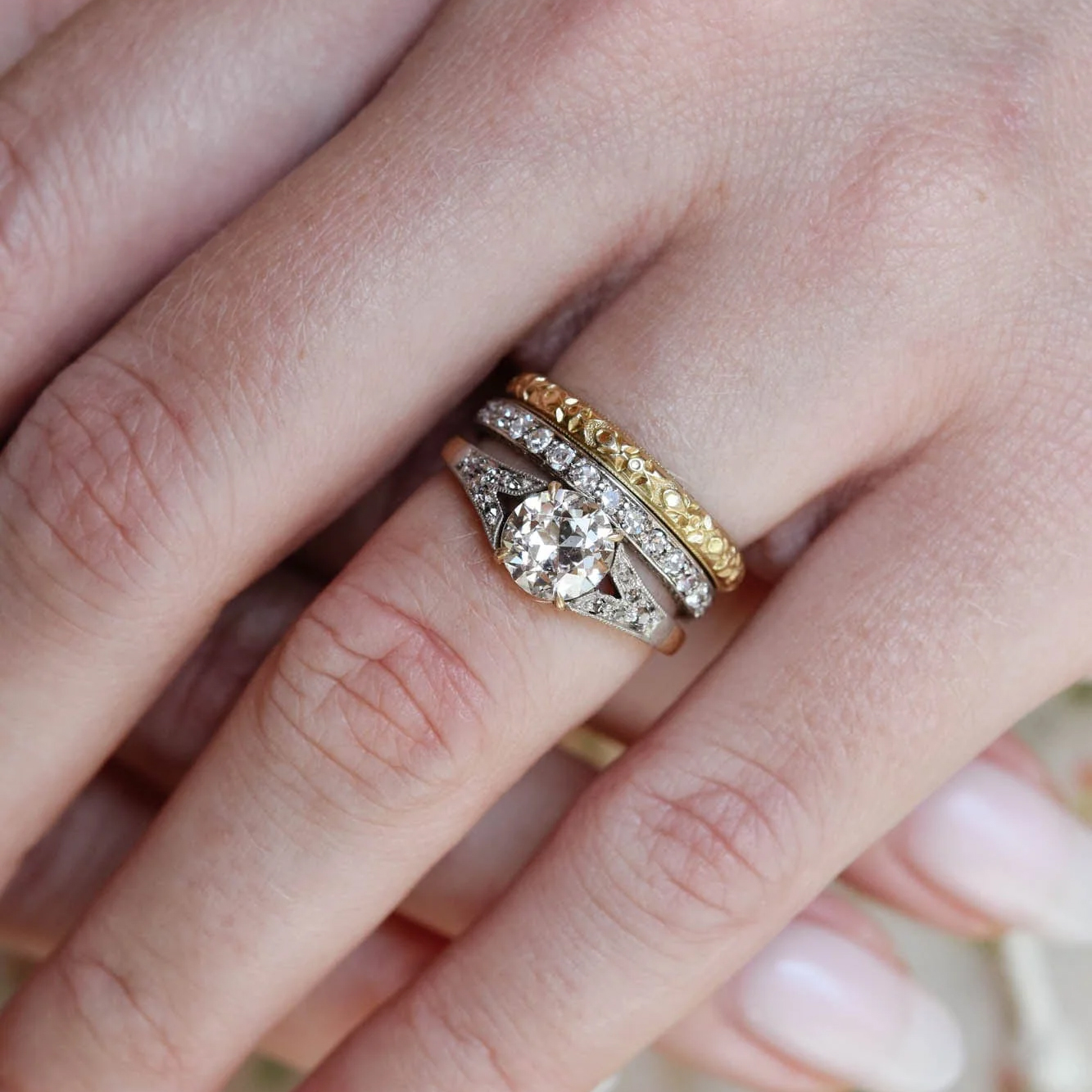 A warm champagne old mine cut diamond solitaire with vintage stacking bands, worn on a hand, the antique look buyers began chasing after the Swift engagement