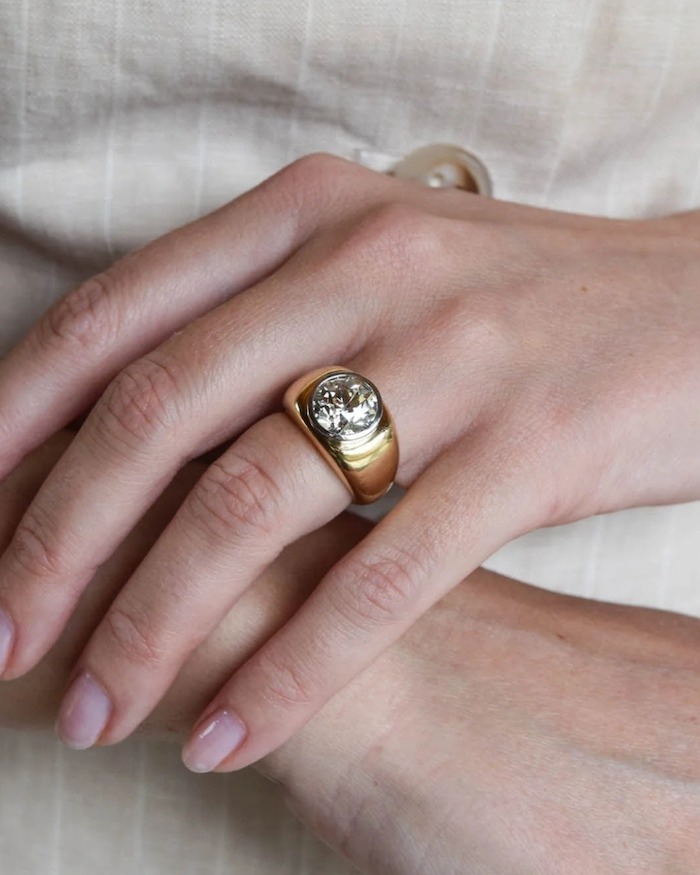 An old mine cut diamond set in a bold gold dome ring, worn on a hand, an antique stone in a modern, maximalist setting