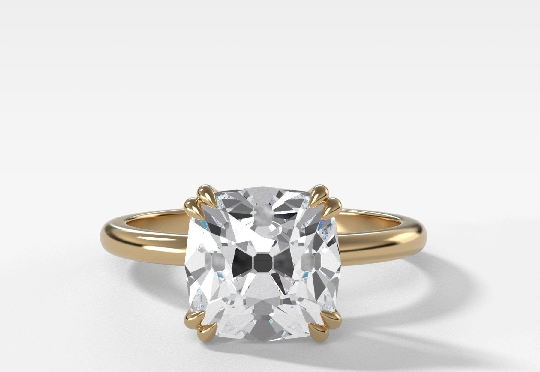 A cushion old mine cut diamond solitaire in yellow gold, showing the high crown and chunky facets that distinguish the cut