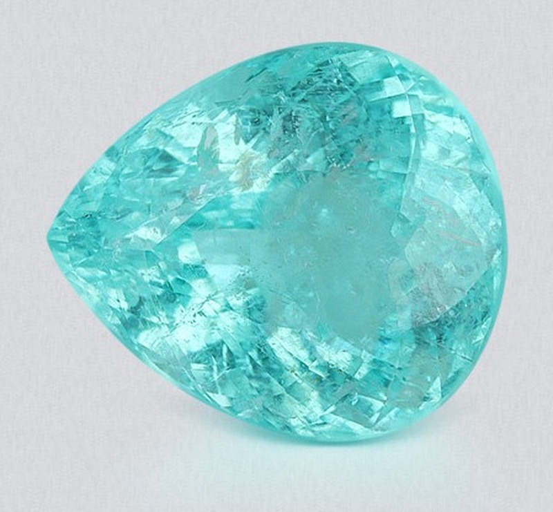 A single loose neon blue-green Paraíba tourmaline, pear cut, the loose Mozambican stone an accessible budget buys before any setting.