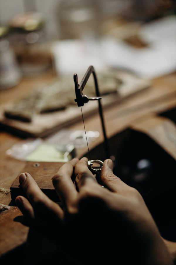 A jeweler cutting a ring at the workbench, shaping the metal and the making that a buyer choosing for herself is paying for