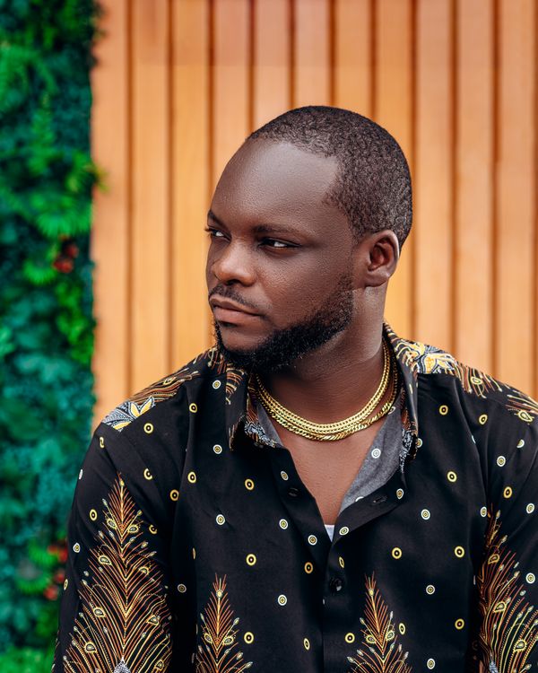 A man in a patterned shirt wearing a gold chain, the kind of open male ornament that predates the plain dark suit