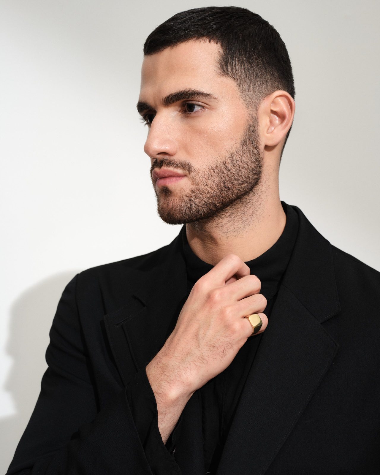 A man wears a solid gold signet ring with a blank, polished face on his ring finger, a gold signet whose value is the metal and the workmanship of the face, with no center stone.