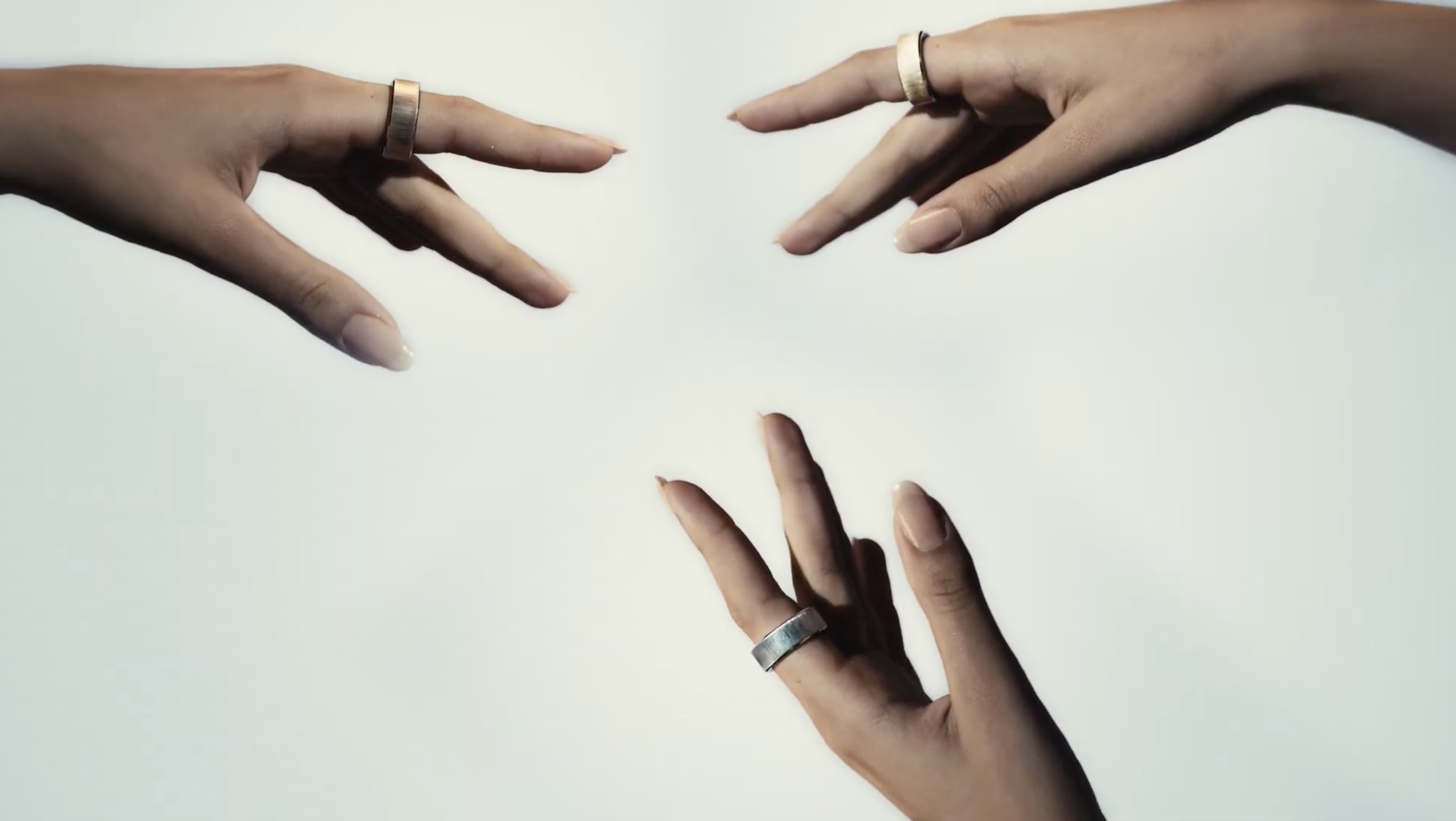 Three hands each wearing an Ultrahuman Rare in solid 18k gold, rose gold, and platinum, the one smart ring that is precious metal all the way through and hallmarked, and the one you have to leave the US to buy.
