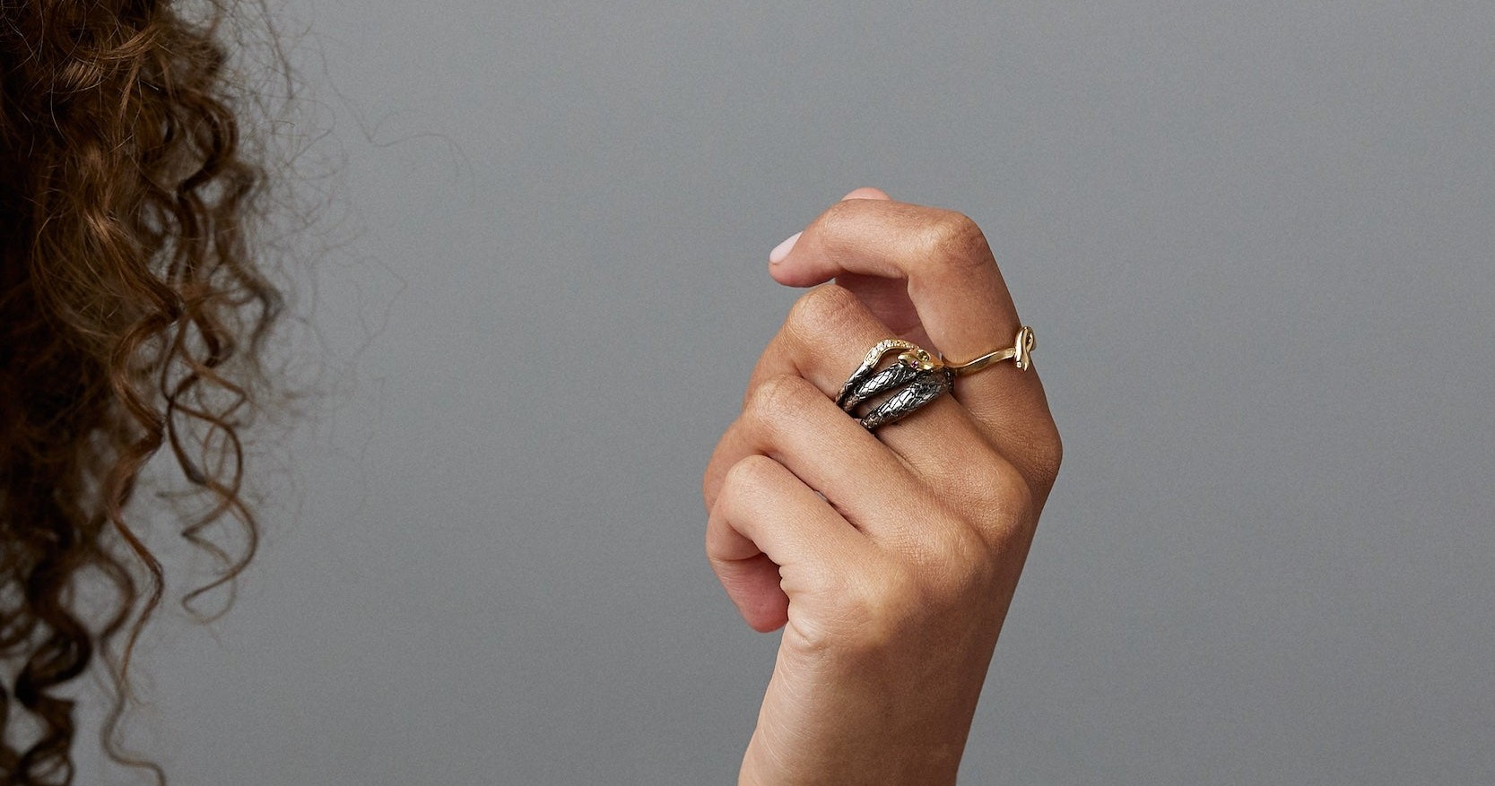 Sorellina Victoria serpent ring and textured gold bangles worn on a raised hand: the kind of distinctive independent design happening one tier below the global jewelry houses