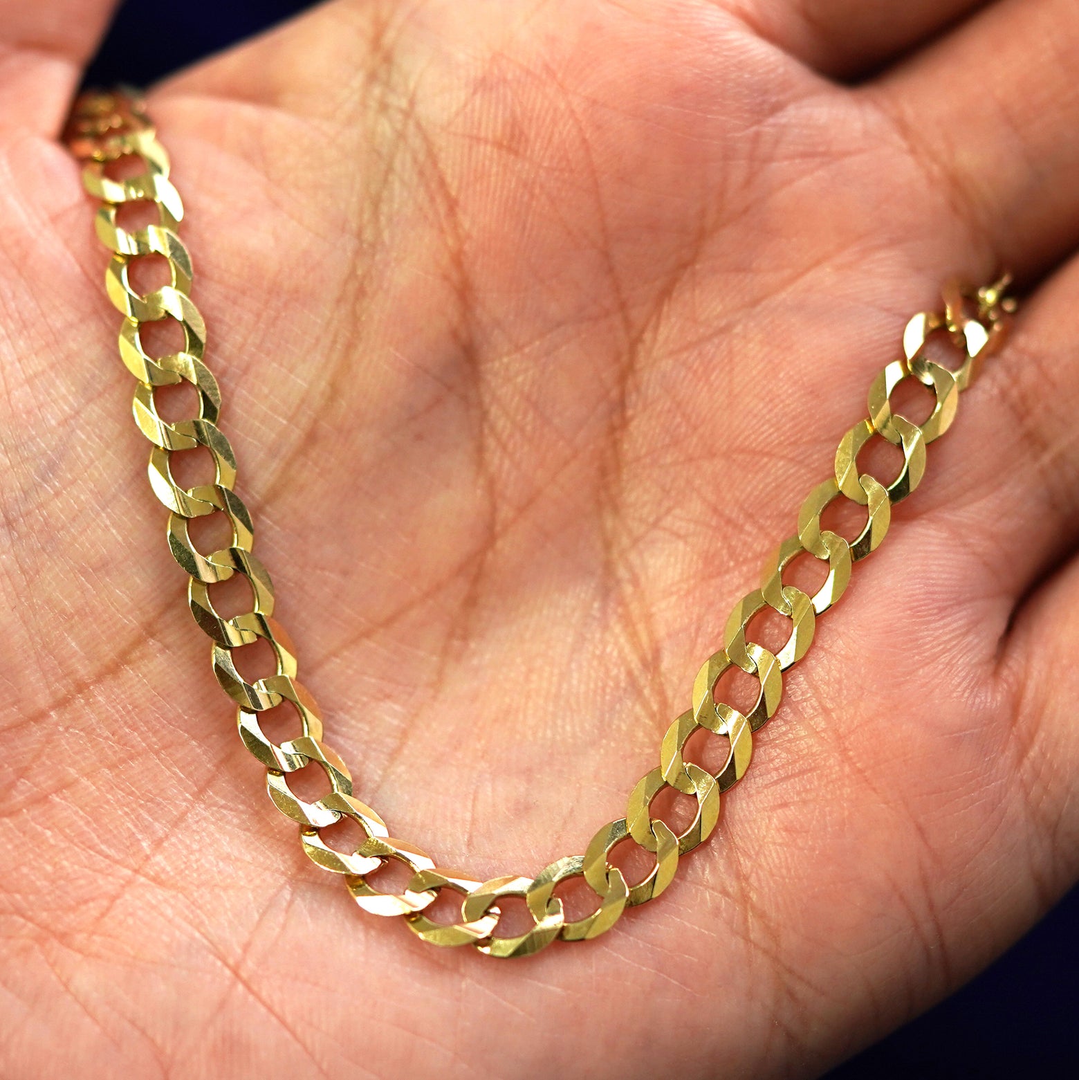 A solid 14k gold curb chain made by a US independent jeweler held in an open hand, the insulated kind of piece that drags no tariff or refund question behind it