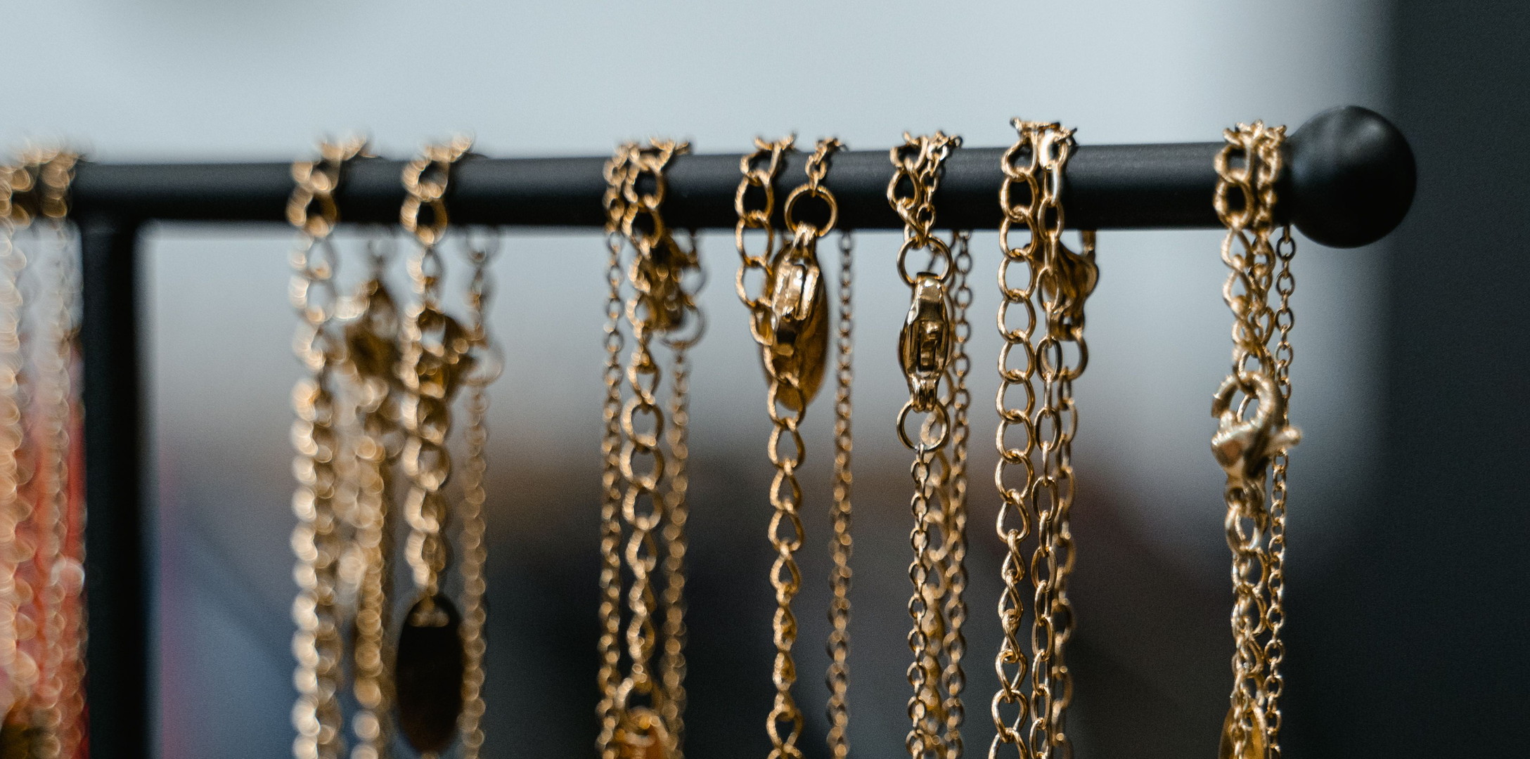 A rack of plain gold chains hanging in a shop, shot close and warm. Every chain looks like the same gold, which is the point: what the karat is comes off the tag, not the look.